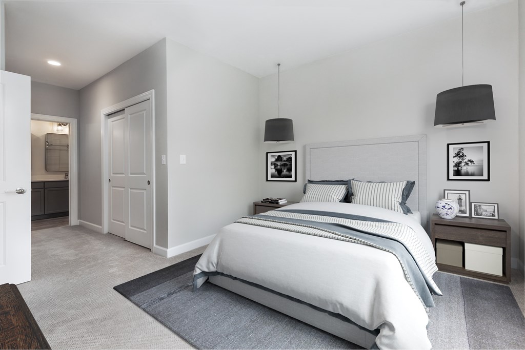 A bedroom with a large bed and a nightstand with a clock on it.