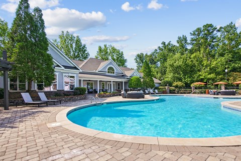 A large swimming pool in a backyard with a house in the background.