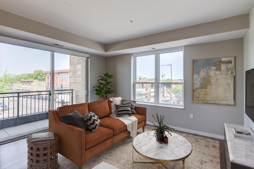 a living room with a brown couch and a table with a plant on top of it