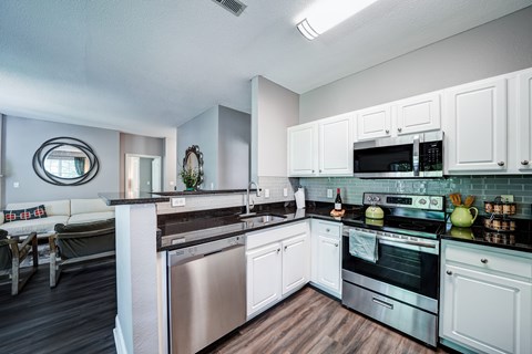 A modern kitchen with white cabinets and stainless steel appliances.