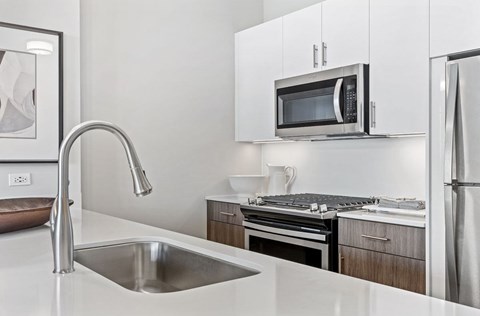A modern kitchen with a stainless steel sink and refrigerator.