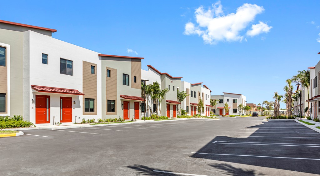 a row of townhomes with red doors and palm trees