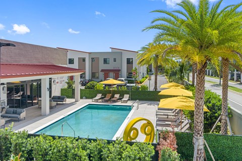 a swimming pool in front of a hotel with palm trees