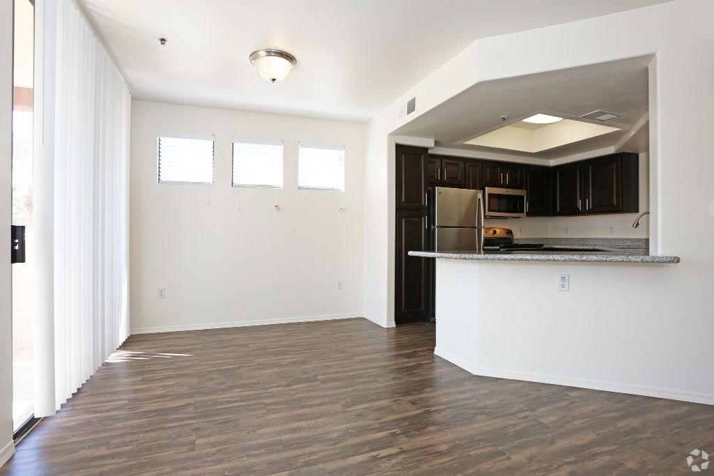 an empty living room with a kitchen and a counter top