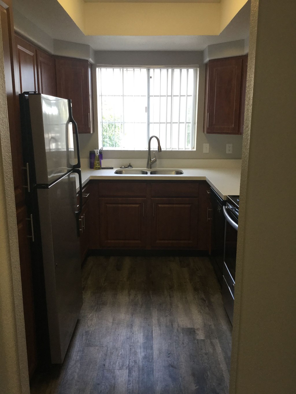 an empty kitchen with wood floors and a large window