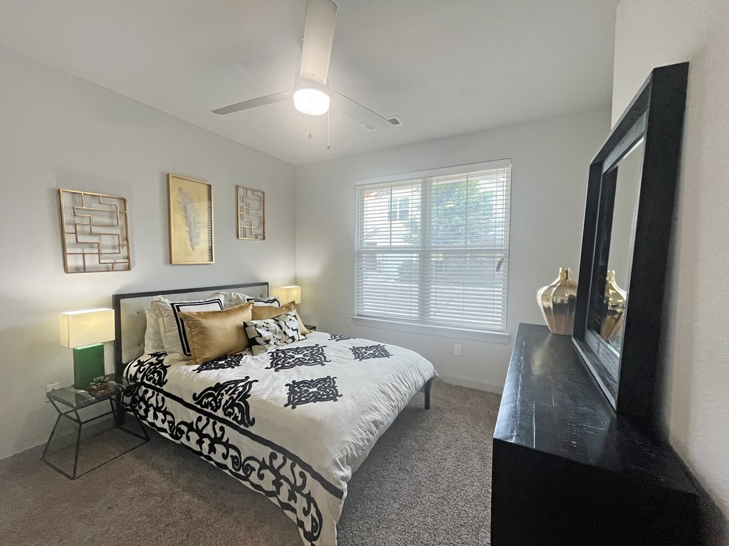 Spacious bedroom with natural light, ceiling fan, and large furniture