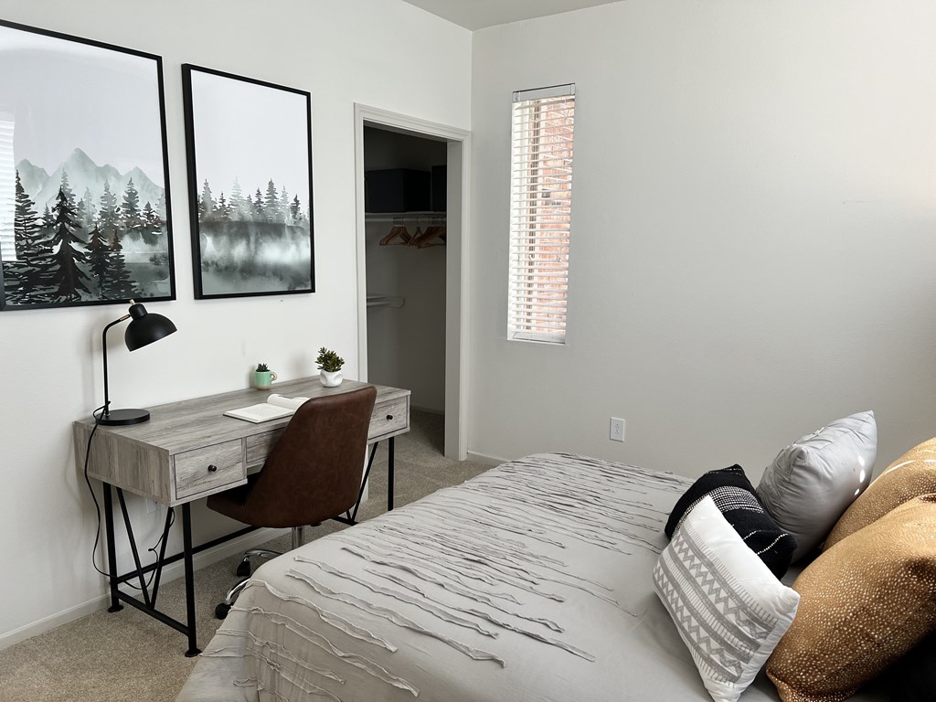 a bedroom with a bed and a desk in a room