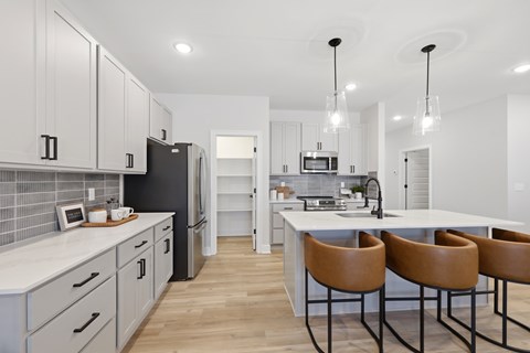 A modern kitchen with a white countertop and brown chairs.
