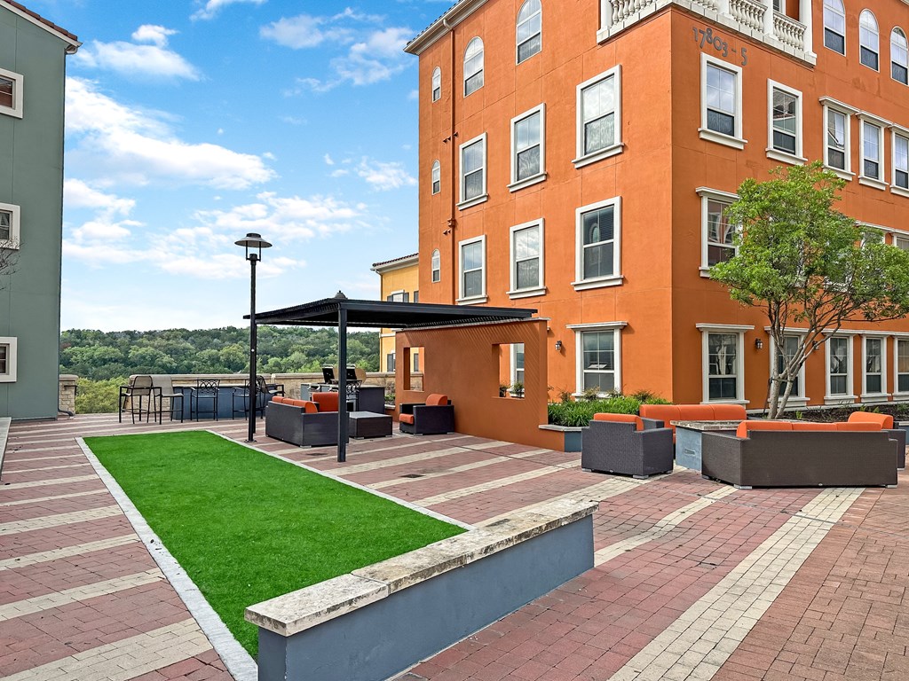 a courtyard with a lawn and a large brick building