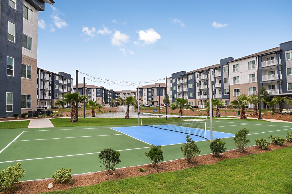 an outdoor tennis court with apartments in the background