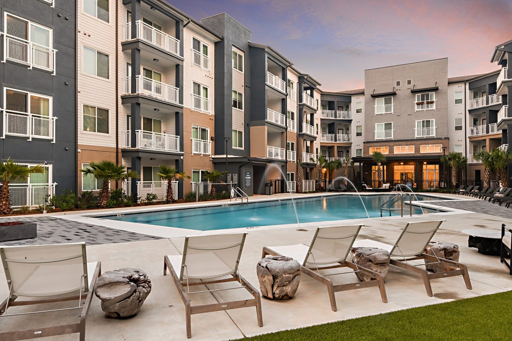 an apartment pool with chairs and chairs around it in front of an apartment building