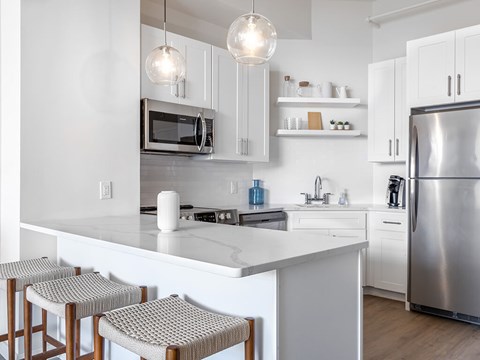 A modern kitchen with white cabinets and a stainless steel refrigerator.