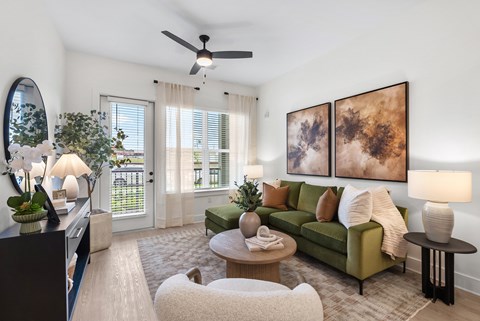 A living room with a green couch and a painting on the wall.