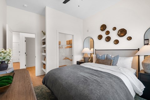 A bedroom with a large bed and a wooden table with a flower pot on it.