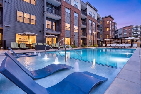 A swimming pool with a slide in front of apartment buildings.