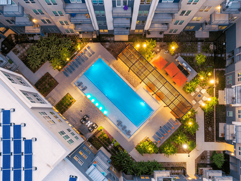 A swimming pool surrounded by apartment buildings at night.