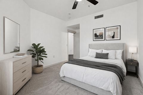 A bedroom with a large bed, a dresser, and a ceiling fan.