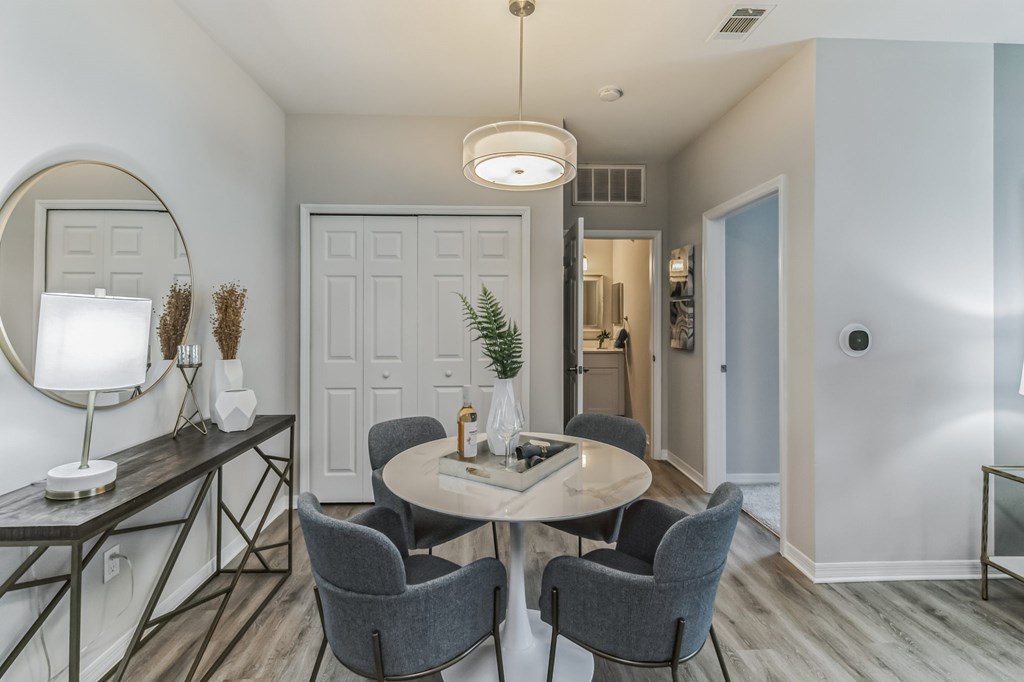 A modern dining room with a round table and grey chairs.