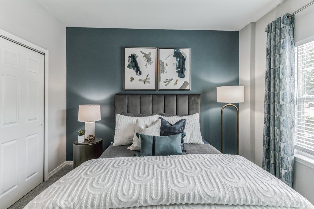 A bedroom with a large bed and two lamps.
