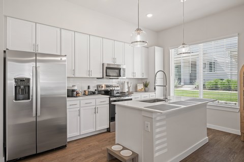 A modern kitchen with white cabinets and stainless steel appliances.