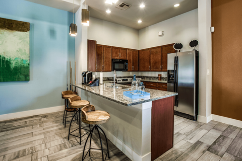 A kitchen with a blue wall and a counter with a refrigerator and microwave.