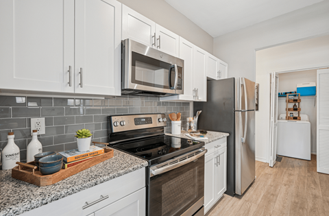 A kitchen with white cabinets and a black refrigerator.