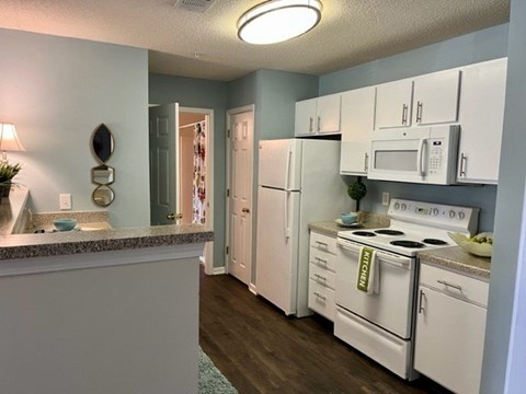A kitchen with white appliances and a grey counter.