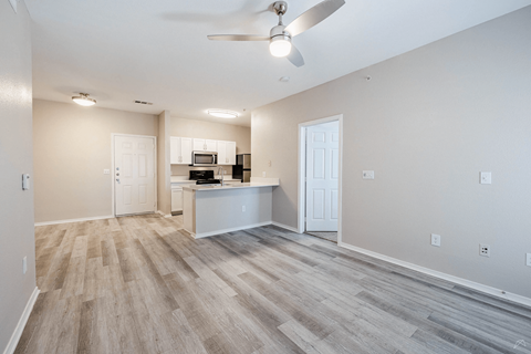 A spacious room with a ceiling fan and light fixture.