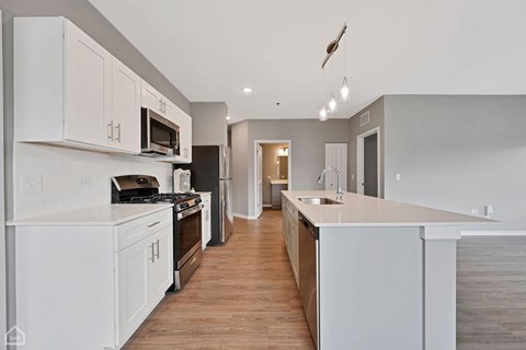 A modern kitchen with white cabinets and a wooden floor.