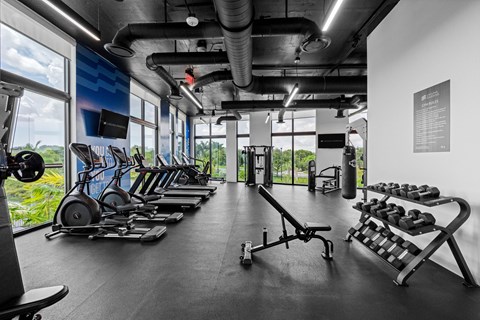 A gym with a variety of equipment including treadmills, weights, and exercise machines.