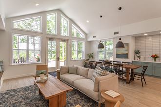 an open concept living room and dining room with large windows and a vaulted ceiling
