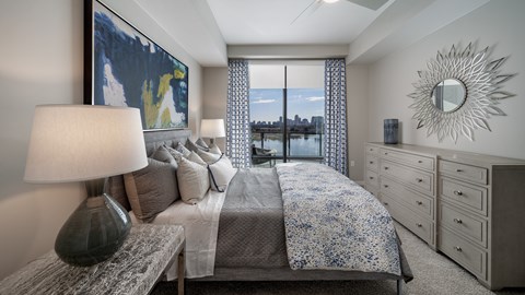 A bedroom with a large bed, a bench, and a painting on the wall.