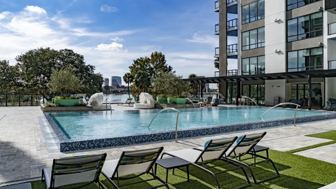 a swimming pool in front of a building with a city in the background