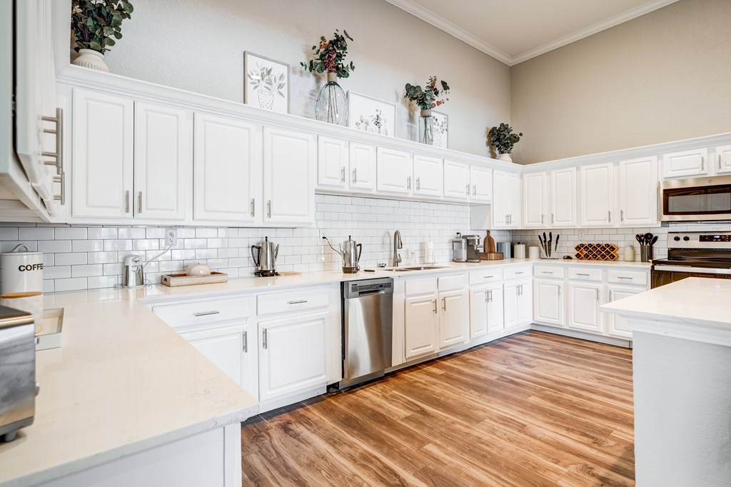 a kitchen with white cabinets and a wood floor