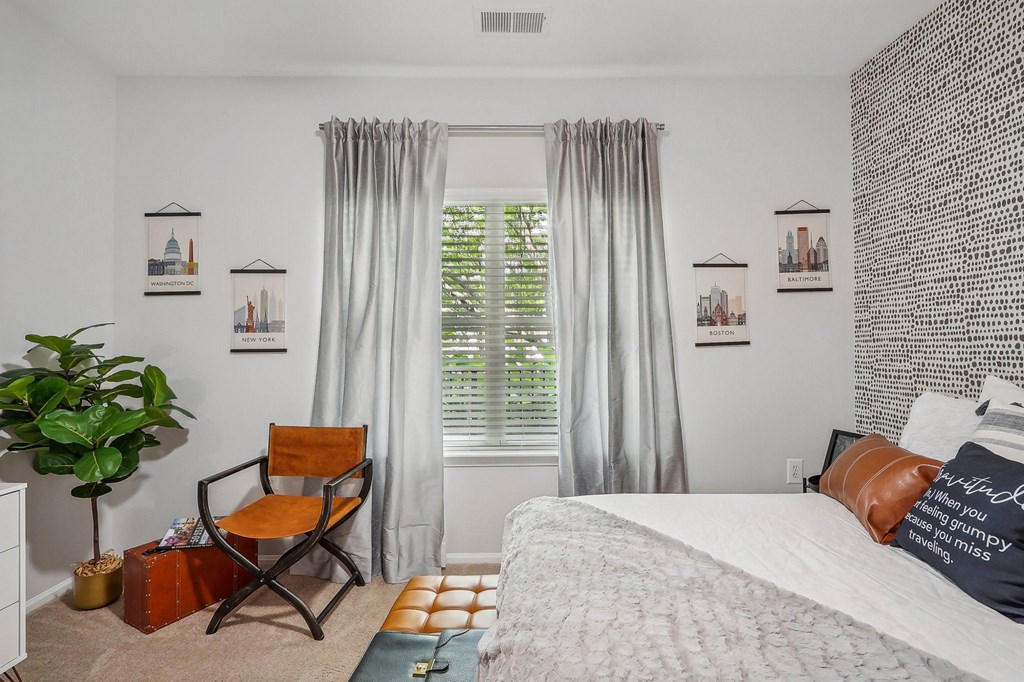 a bedroom with a bed and a window with curtains and a chair