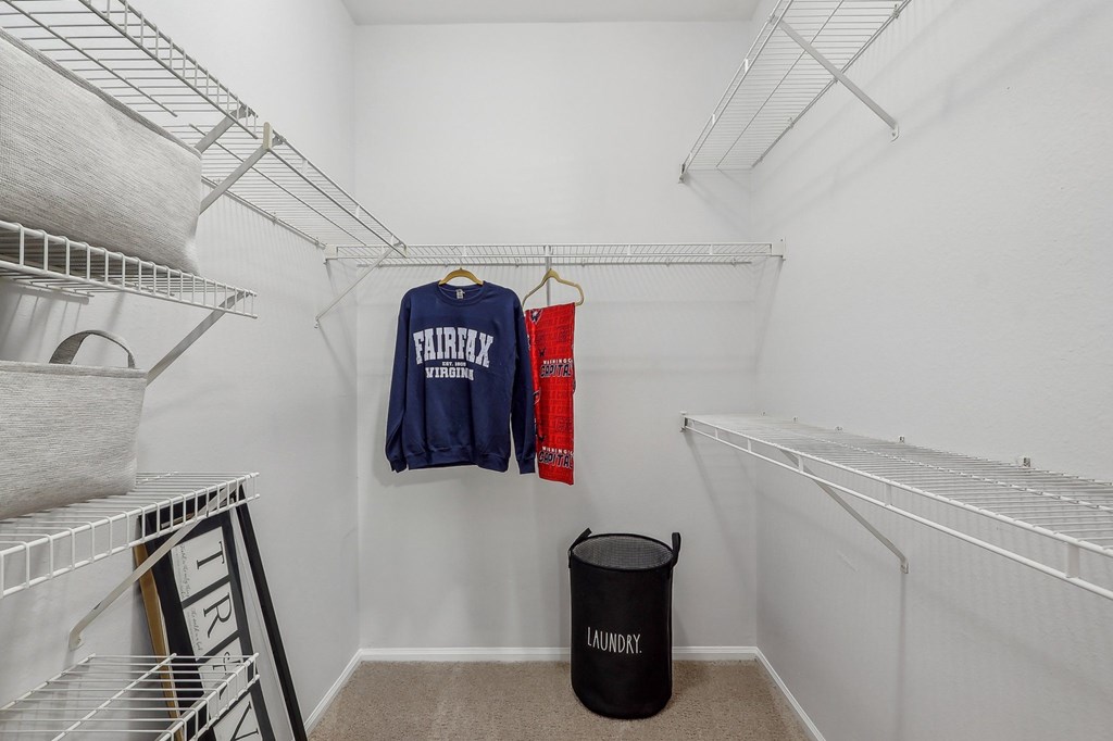 a walk in closet with white walls and white racks and a laundry room with clothes