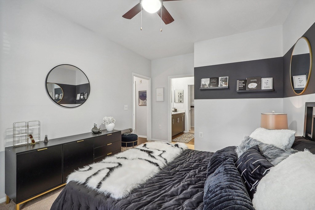 a bedroom with a black and white bed and a mirror