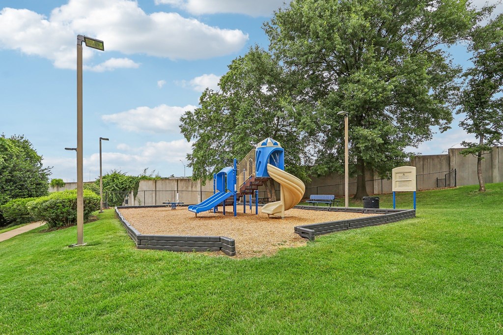 a playground with a blue and yellow slide in a park