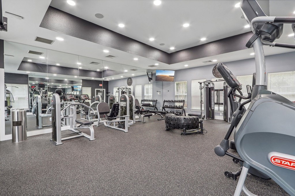 a gym with weights and cardio equipment at the enclave at university heights