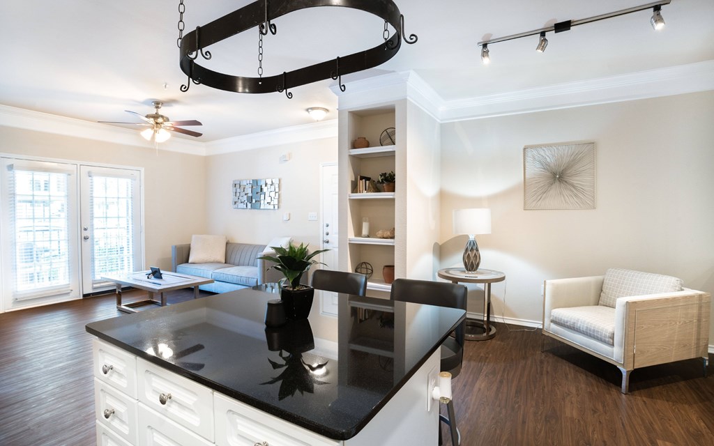 a kitchen with a center island and a living room in the background