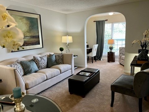 A living room with a white couch, a coffee table, and a painting on the wall.