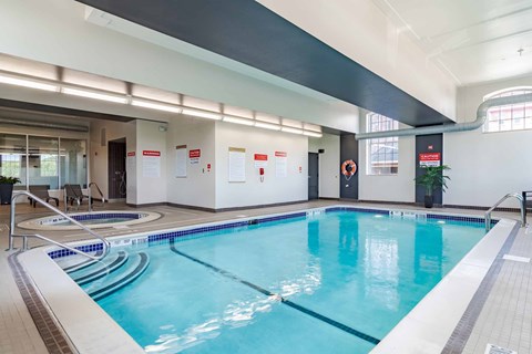 A large indoor swimming pool with a blue tinted water.