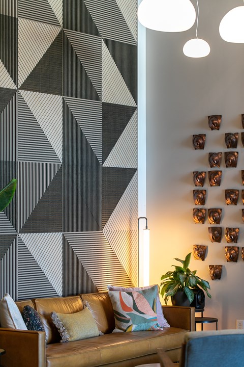 A living room with a brown couch and a geometric wall mural.
