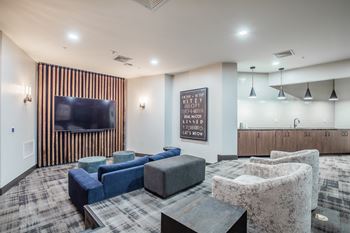 A living room with a grey sofa, a black coffee table, and a TV on the wall.