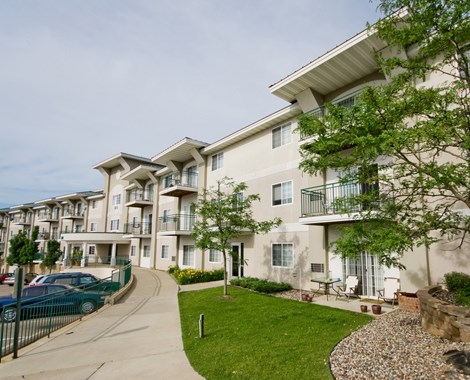 a row of apartment buildings with cars parked in front of them