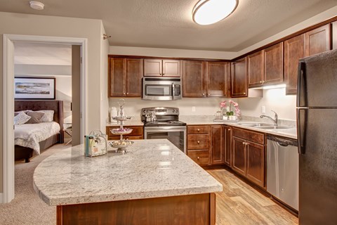 A kitchen with a marble countertop and wooden cabinets.