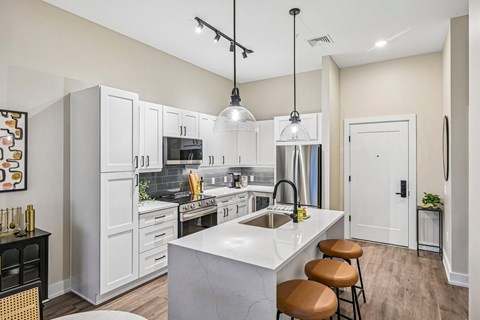 A kitchen with white cabinets and a marble countertop.