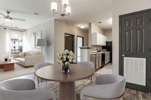 A modern dining room with a round table and grey chairs.