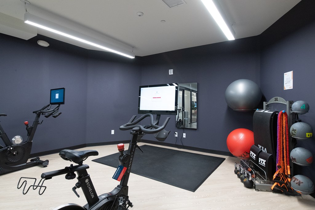 a fitness room with exercise equipment and a large screen