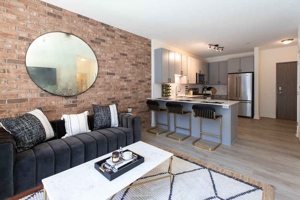 a living room with a couch and a coffee table in front of a kitchen with an island